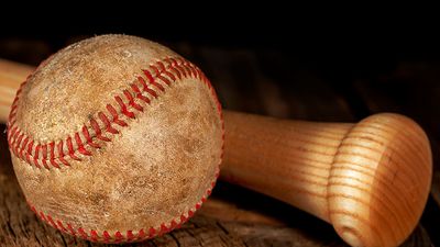 An old worn baseball and wood bat