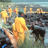 Workers pressure cleaning rocks coated in oil from the Exxon Valdez oil spill, March 1990. In the intertidal zone, Prince William Sound, Alaska. pollution disaster