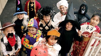 Children dressed in halloween costumes and masks. Group of trick or treaters standing on steps in their Halloween costumes. Holiday