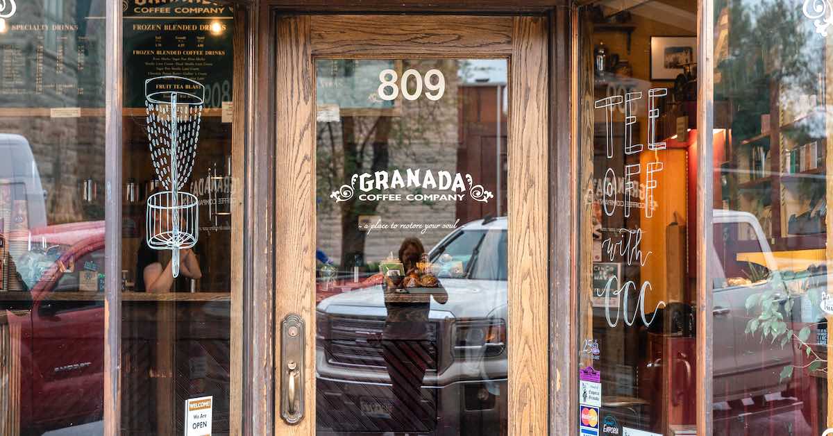 Photo of a coffee shop interest with large glass windows, one of which has a disc golf basket drawn on it