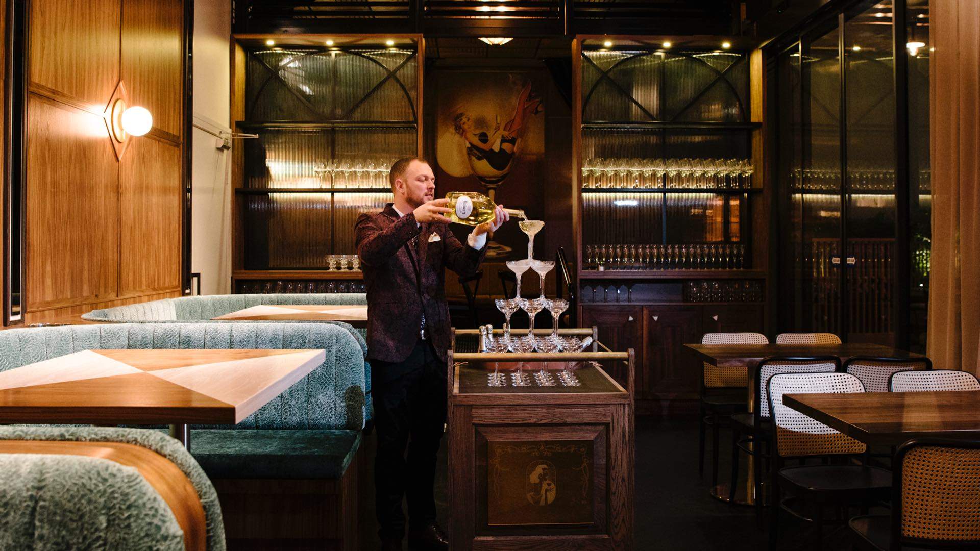 A man pouring Champagne on a tower of champagne glasses at Nick and Nora's - one of the best bars in Sydney - paramatta