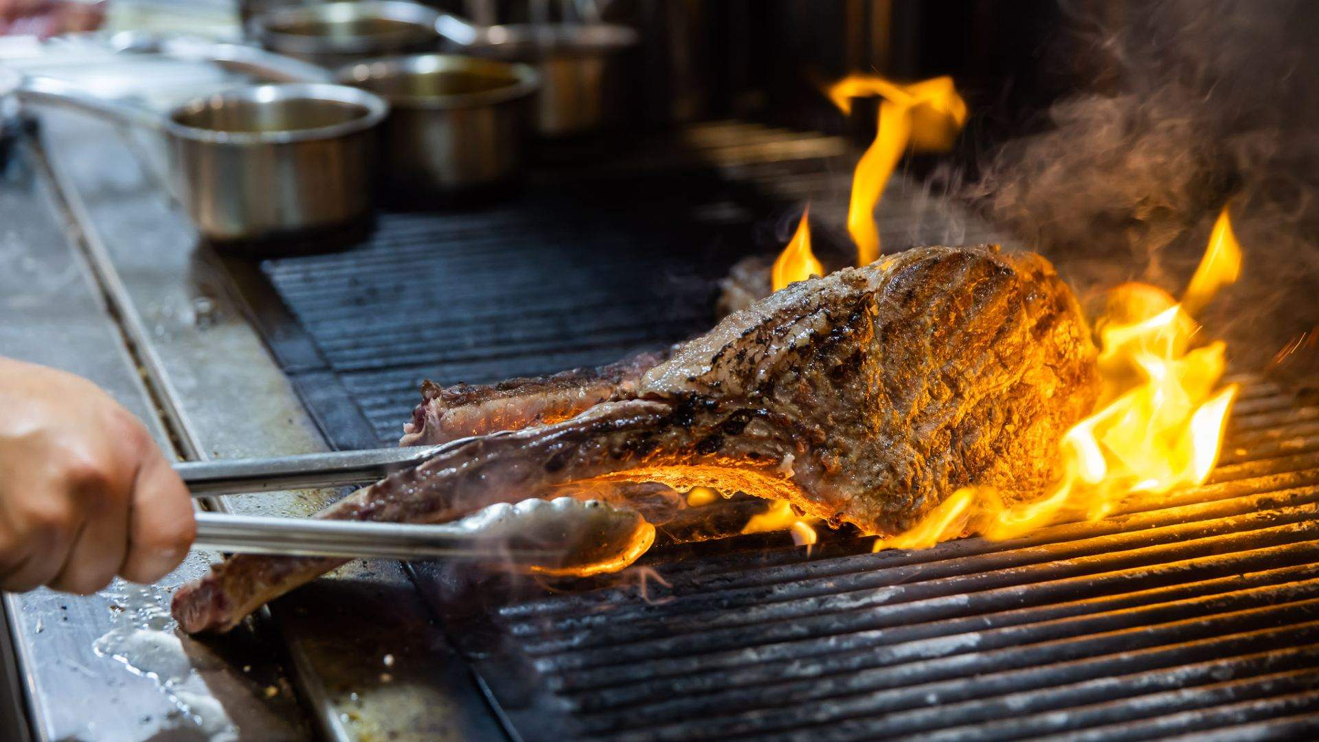 a steak being cooked on the grill with flames at Botswana Butchery - home to some of the best steaks in sydney