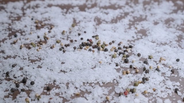 A wooden spoon with pepper falls on a table