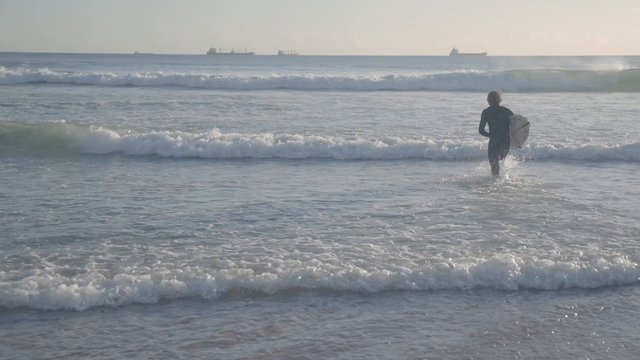 Surfer Braving the Waves: Preparation and Entry into the Ocean