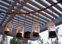 Four mason jars hanging with tea lights hanging from pergola