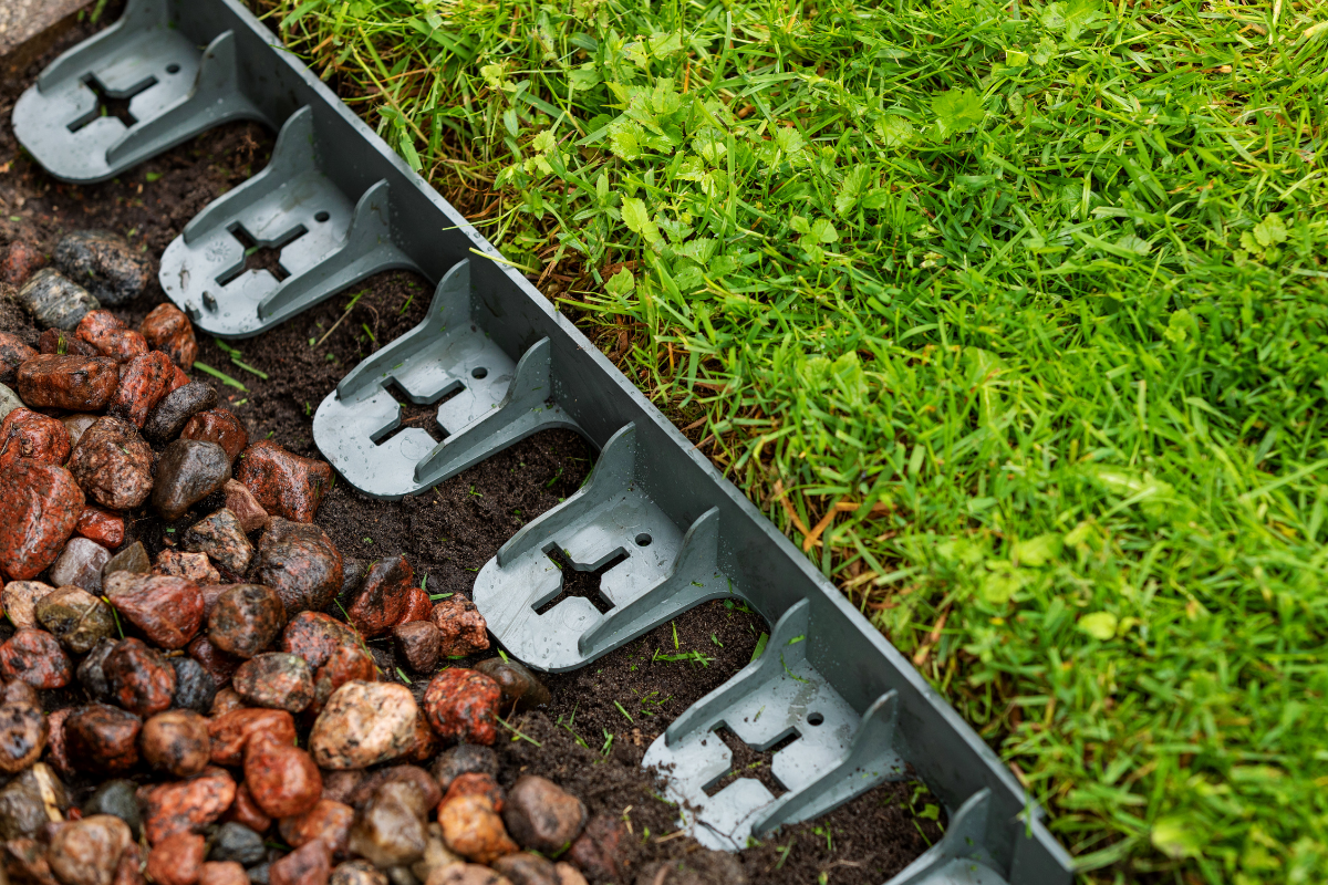 plastic lawn edging up against grass with rocks on other side