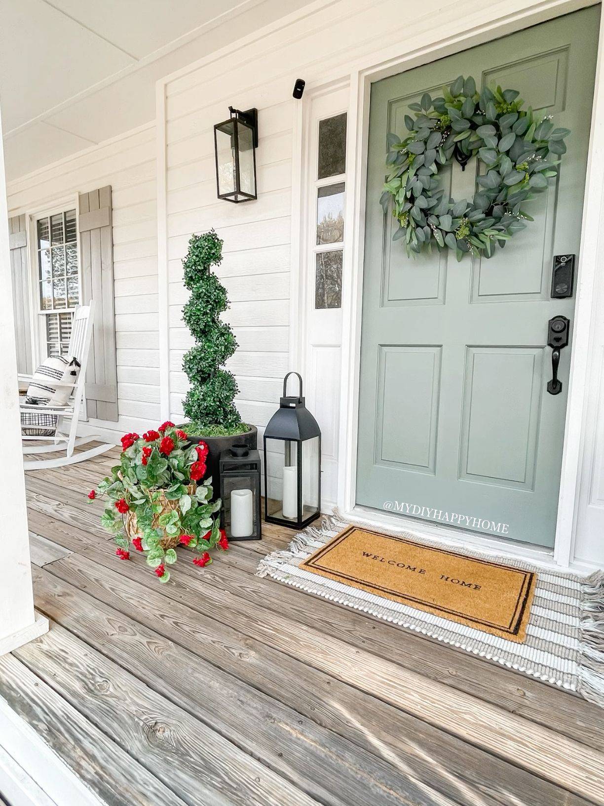 A sage green door with a wreath on it.