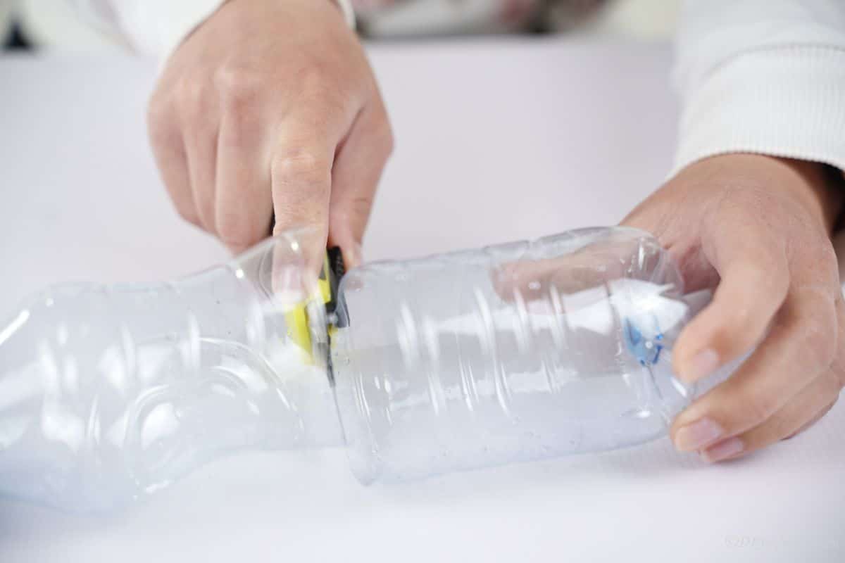 hand cutting an empty bottle in half