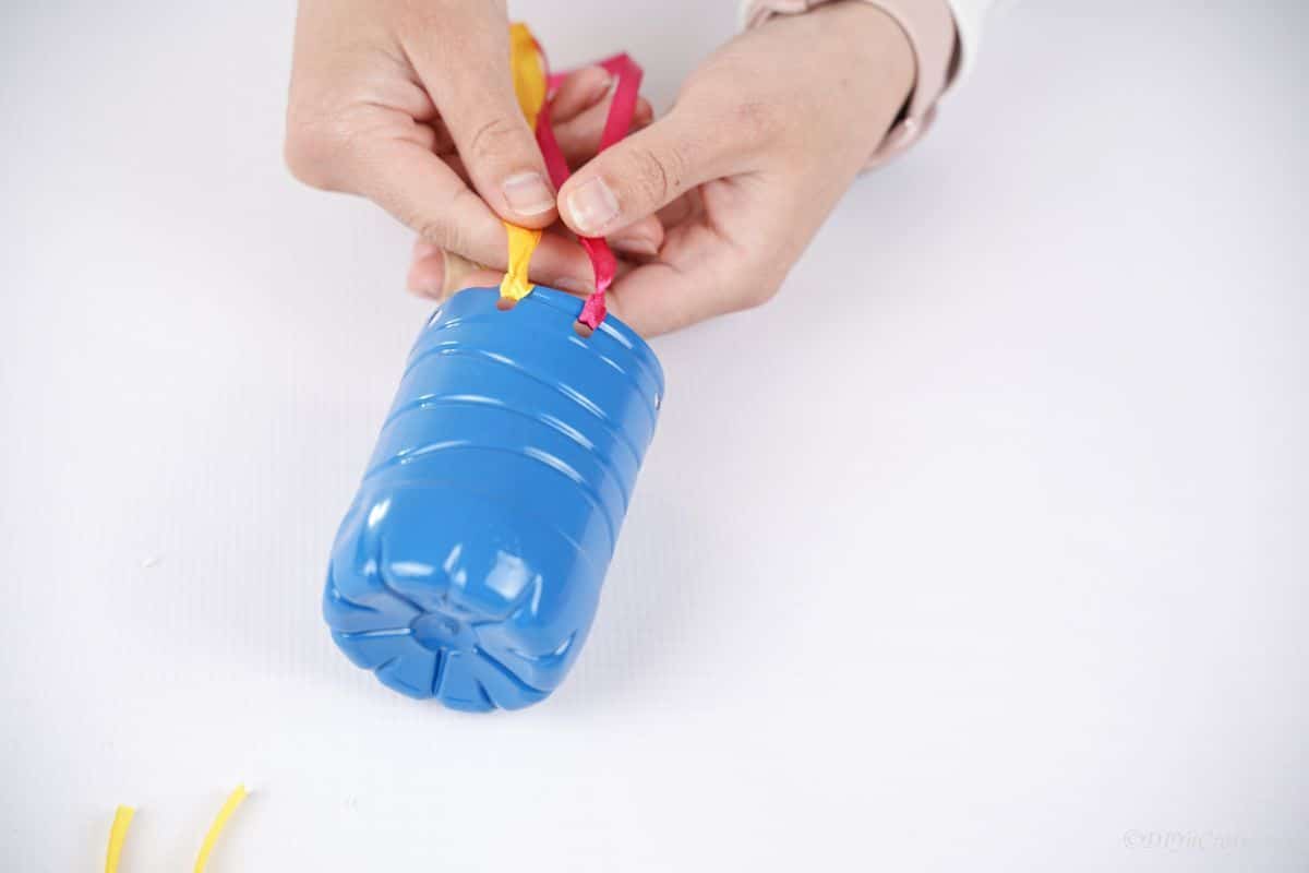 pink and yellow ribbon tied onto blue plastic bottle