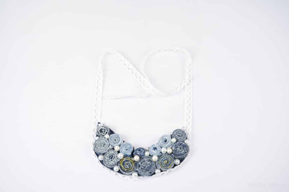 denim necklace on white table