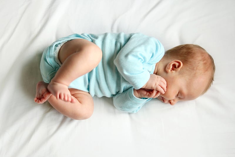 a newborn baby sleeping peacefully on bed in white sheets