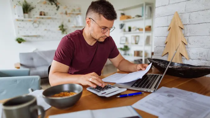 Young man at home, paying bills online.