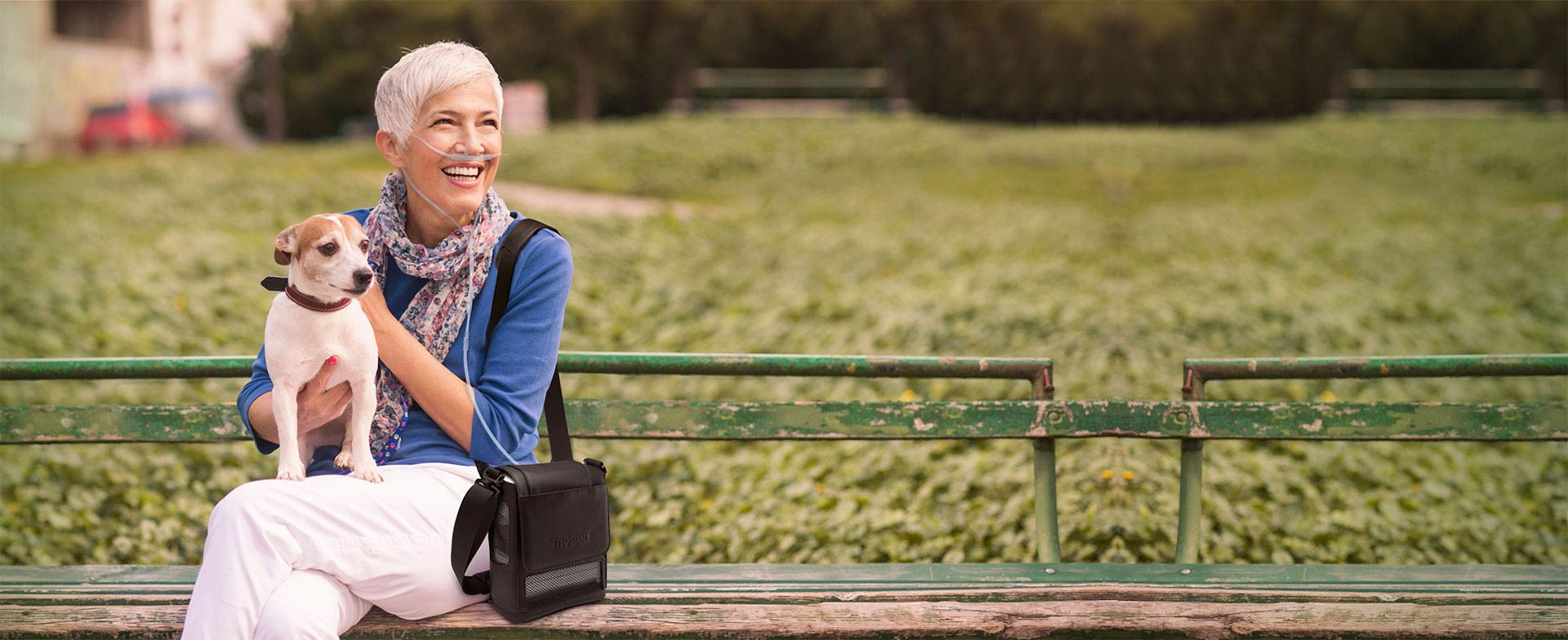 Woman and dog on a park bench with an Inogen Portable Oxygen Concentrator