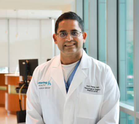 Dr. Akil Patel smiling at the camera in clinical hallway