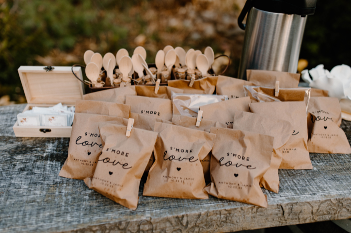 Wooden table outside with tea and coffee with brown bags with kit for s'mores in each