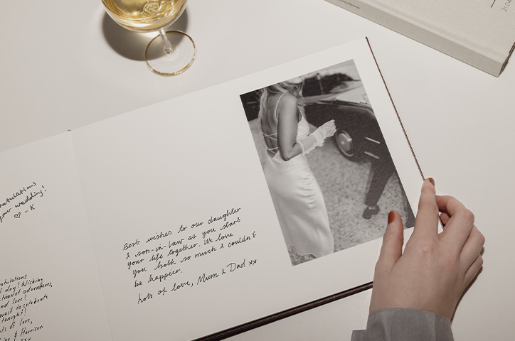 Flipping the pages of a Wedding Guest Book with handwritten messages inside and champagne glass next to book