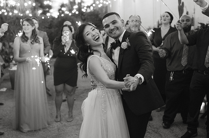 Couple dancing together at wedding reception party, guests forming a crowd around them holding sparklers