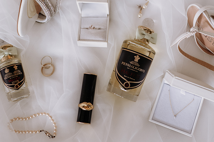 Flatlay of wedding day accessories including jewelry, perfume and bridal shoes