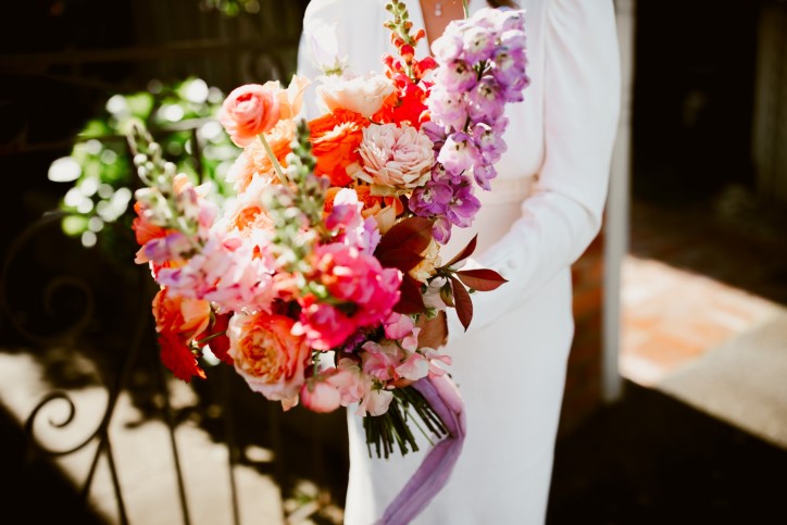 Bride holding colorful pink red and purple wedding bouquet