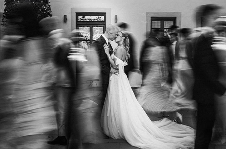 Bride and groom kissing while people are dancing around them