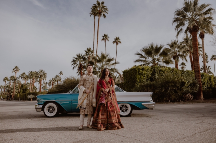 Newlywed couple in traditional dress with palm trees in the background