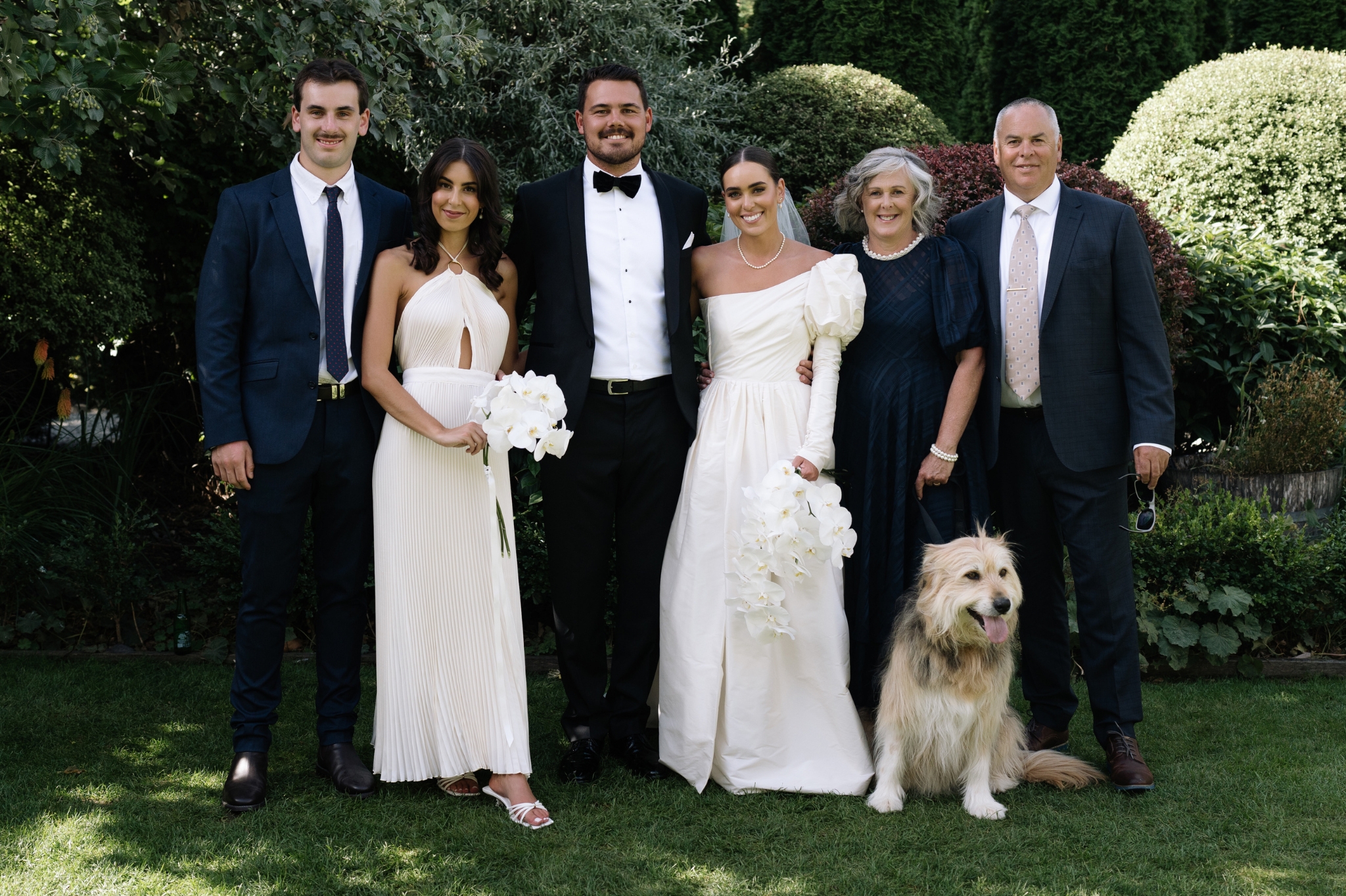 Bride and Groom with their family and dog at their wedding in a garden