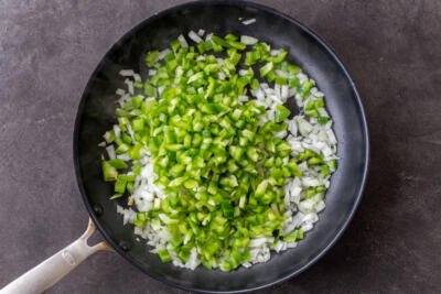 Bell peppers and onions in a pan cooking.