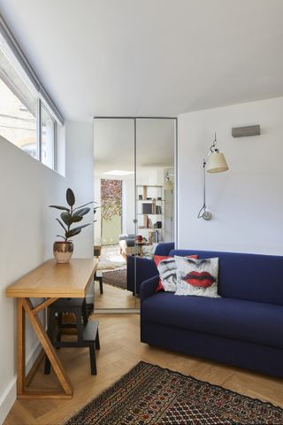 Small living room with blue velvet sofa and mirrored corner cabinet