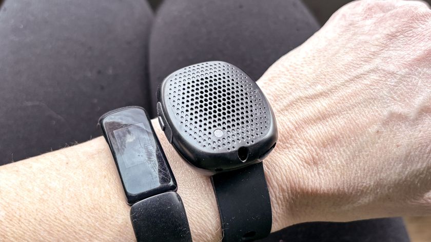 The Silent Beacon Bluetooth panic button worn on a wrist next to a Fitbit