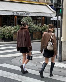 two women crossing street in brown jackets and black skirts