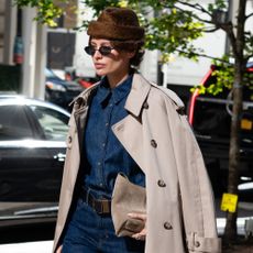 a woman wears a brown furry hat with a denim shirt