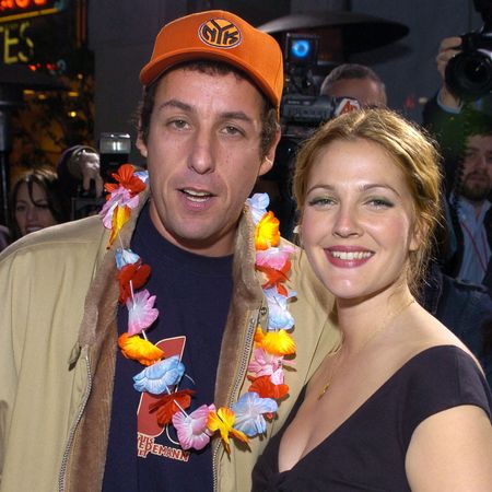 Drew Barrymore wears an off-the-shoulder black top as she laughs next to Adam Sandler on stage at an awards show, while they both hold popcorn trophies, and at the 50 First Dates premiere, Drew Barrymore wears a black cut-out dress and Adam Sandler wears a tan jacket and baseball cap