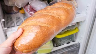 White loaf in plastic wrapper being placed in freezer