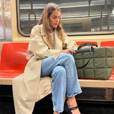 Vee Collective founder Lili Radu wearing a trench coat, jeans, Miu Miu ballet flats, and a Vee Collective Porter Tote in NYC