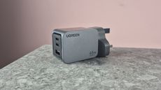 UGreen Nexode Pro 65W 3-Port Charger on stone surface against pink background