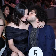 LOS ANGELES, CALIFORNIA - OCTOBER 24: (L-R) Benny Blanco kissing Selena Gomez's cheek at the Second Annual Rare Impact Fund Benefit Supporting Youth Mental Health, hosted by Selena Gomez, at Nya Studios on October 24, 2024 in Los Angeles, California. She's wearing an off-the-shoulder dress with a short bob and he's in a navy suit. 