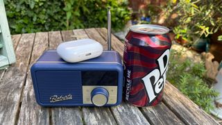 Roberts Revival Petite 2 internet radio next to AirPods case and Dr Pepper can