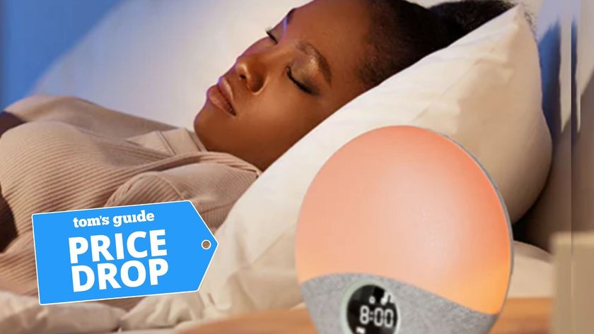 A woman in bed sleeping next to Momcozy Sunrise Sound Machine Wake-Up Light