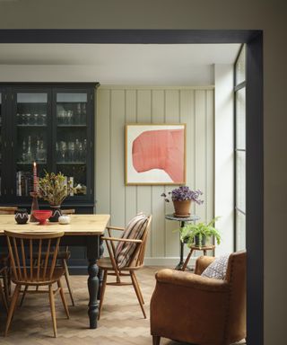 dining room with light green panelled walls, wooden table and dark gray dresser