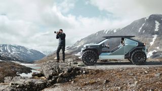 Man taking photograph on mountain beside utility vehicle