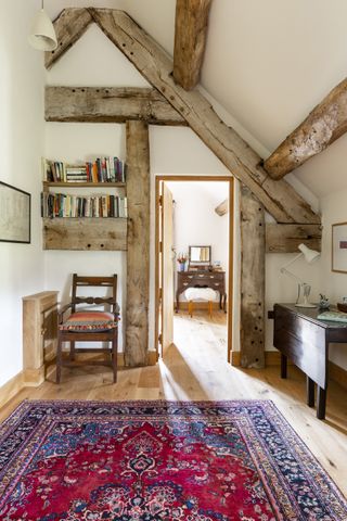 Reading nook with chair and shelving, side table, wood floor and red patterned rug