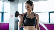 Woman performing a bicep curl using a dumbbell in her right hand