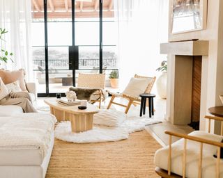 Relaxed, mindful living space in neutral and white, with relaxed textures, wooden furniture in light tones, and layered rustic rug & fluffy faux fur.