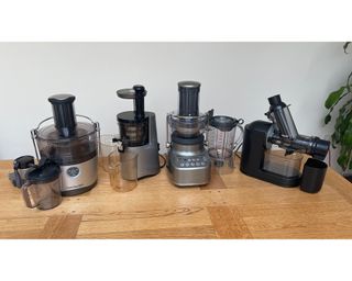 A selection of juicers on wooden surface including the Philips Viva Masticating Juicer, NutriBullet Pro, Sage 3X Bluicer and Hurom H-AA slow juicer