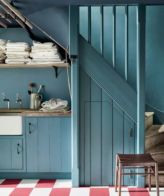 Kitchen color drenched in light blue paint, paired wityh a red and white chequered floor