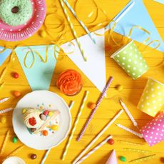 Party plates, cups and bunting on yellow table