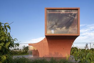 One of the pavillions of the arts and culture center is built in an arc shape, with an all-glass wall at the end. It sits in the peach tree orchard.