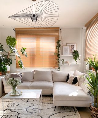 Japandi style space with feature hat style pendant, chaise sofa, and plenty of houseplants.