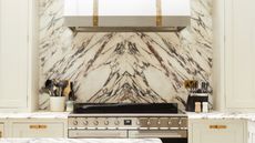 white and gold kitchen ideas, marble and white kitchen with white cooker hood with brass detailing, chrome and black oven, marble backsplash, marble countertops, utensils,