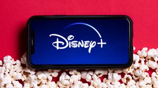 The Disney Plus logo on a phone surrounded by popcorn